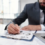 businessman writing on clipboard closeup