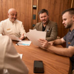 physicians discussing papers with man at desk